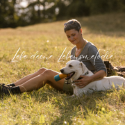 Claudia Edelmayer-Murri sitzend auf Himmelwiese im Sonnenuntergang mit ihrem Hund Leo